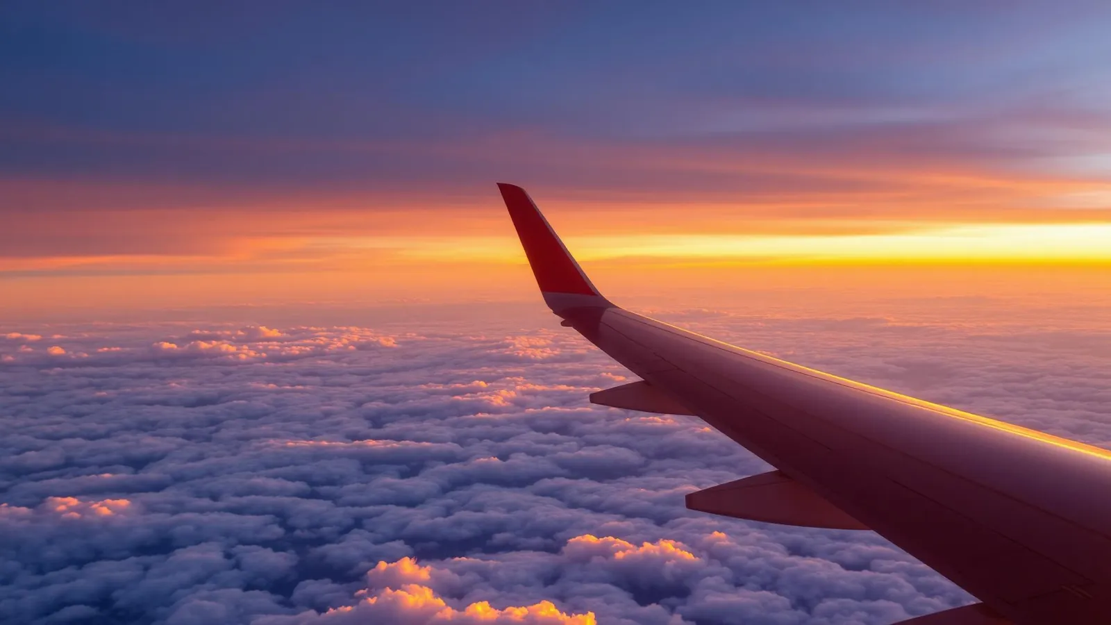Aircraft wing above sunset clouds